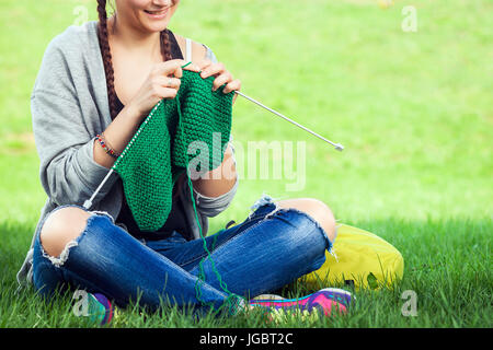 Jeune femme à la mode tricote un chandail blanc sur un tricot vert lumineux sur l'herbe un jour d'été Banque D'Images