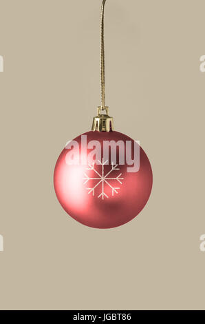 Une seule boule rouge, suspendu à la partie supérieure du châssis sur une chaîne et fermoir dieu, décorée d'une étoile au centre du flocon. Fond or. Banque D'Images