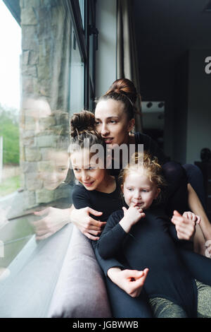 Maman et deux filles ensemble à la fenêtre Banque D'Images