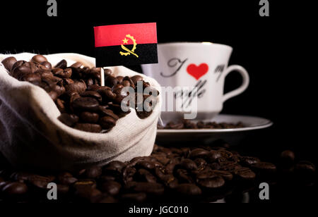 Drapeau de l'Angola dans un sac avec les grains de café isolé sur fond noir Banque D'Images