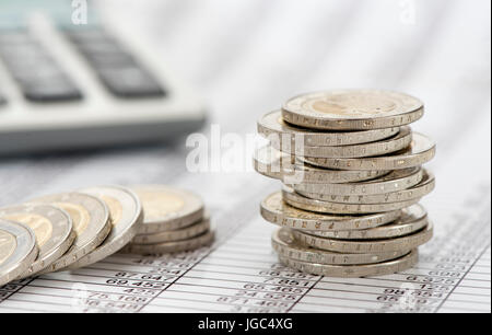 Les pièces en euros empilés avec calculatrice et graphique Banque D'Images