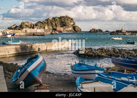 Fihing bateaux hors de l'eau dans une journée d'hiver froide et venteuse au port d'ACI Trezza. Île de Lachea sur fond. Ville métropolitaine de Catane, Sicile, Banque D'Images