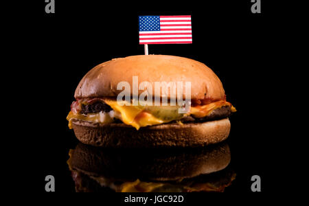 USA flag on top of hamburger isolé sur fond noir Banque D'Images