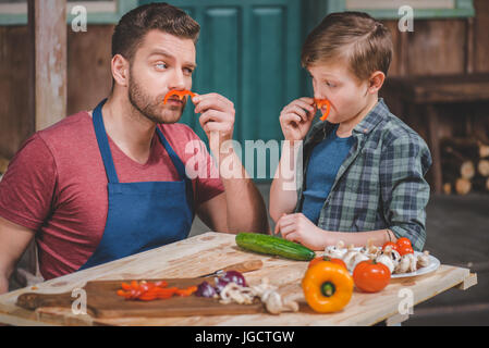 Tablier en père et petit fils s'amusant avec des moustaches poivre, père et fils concept de cuisine Banque D'Images