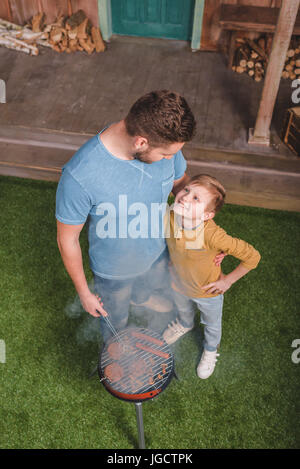 Portrait du père et fils de hamburgers et saucisses hot-dog sur barbecue Banque D'Images