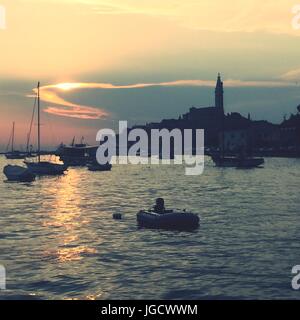 Vue sur la mer et le coucher du soleil derrière la vieille ville de Rovinj en Croatie Banque D'Images