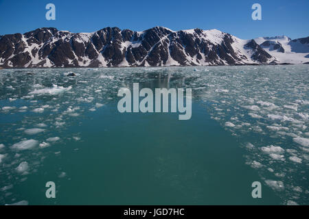 La encore, l'eau claire d'une baie à la langue d'un glacier est parsemé de fragments de glace flottante d'un récent événement de mise bas, avec un chemin clair balayée par un bateau. Banque D'Images