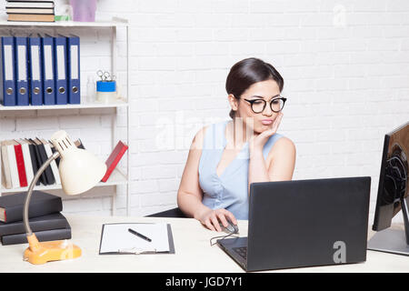 Fille d'affaires se trouve dans un bureau derrière un bureau avec un ordinateur Banque D'Images