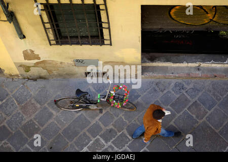 Homme marchant passé une bicyclette sur une rue de Florence Banque D'Images