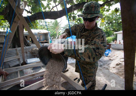 L'ÎLE Betio, Tarawa, Kiribati ATOLL- Cpl. William Tuttle verse de la terre dans un tamis dans un effort pour aider à la Deuxième Guerre mondiale, un charnier d'excavation, le 13 juin 2017, dans l'Île Betio, Tarawa, Kiribati Atoll. La terre a été prise près d'un lieu de sépulture et sera examiné pour les os, du métal et d'autres artefacts. Les Marines et les marins qui ont été incapables de travailler avec les os fragiles de la personne décédée, de sorte qu'ils ont aidé avec de remplissage de trous et de transporter la saleté. Pas de photos de la demeure ont été prises par respect pour les défunts et leurs familles. Tuttle est un spécialiste de l'emballage contre Logisti Banque D'Images