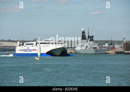 Catamaran Brittany Ferries Normandie Express passant HMS Daring sur son chemin vers l'extérieur du port de Portsmouth. Banque D'Images