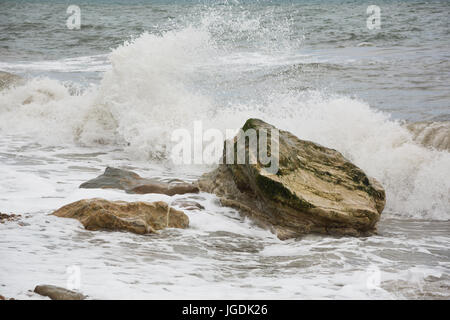 Vue sur la mer de la côte de vagues se briser sur la rive au-dessus gros rocher à l'Eype plage, Symmondsbury, près de Bridport, Dorset, UK. Banque D'Images