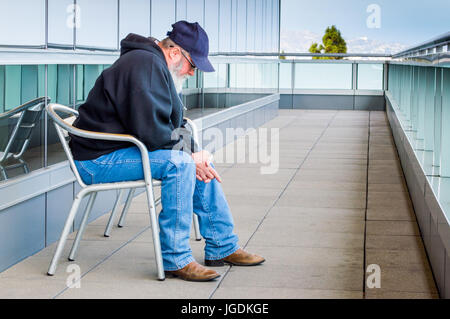 Middle aged man sitting par lui-même sur un balcon avec vue sur ville Banque D'Images