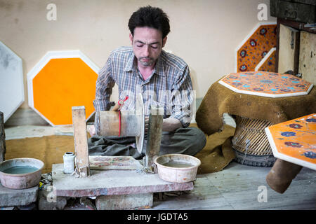 L'homme à la peau pâle en Inde l'élaboration de morceaux de marbre et pierres semi-précieuses sur une main-powered emery à la roue près de Taj Mahal Banque D'Images