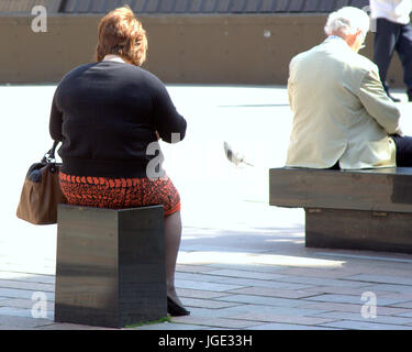 Grande dame obèses de manger tout en étant assis sur un siège approprié vu de derrière Banque D'Images