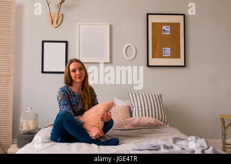 Portrait of smiling Caucasian woman sitting on bed Banque D'Images