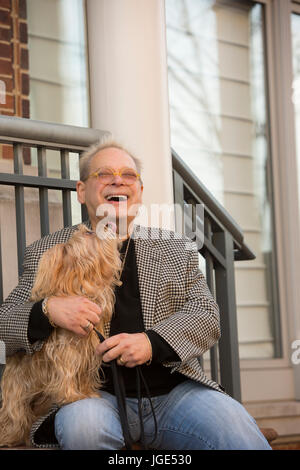 Portrait of Caucasian man sitting on stoop holding dog Banque D'Images