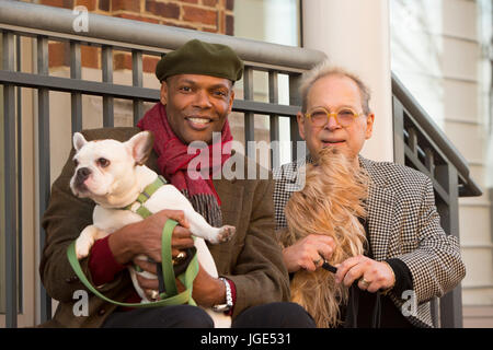 Portrait d'hommes assis sur stoop holding dogs Banque D'Images