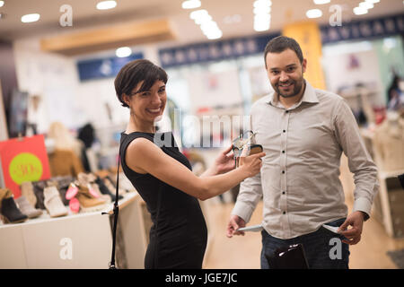 Un jeune beau couple change le regard avec de nouvelles chaussures Magasin de chaussures à Banque D'Images