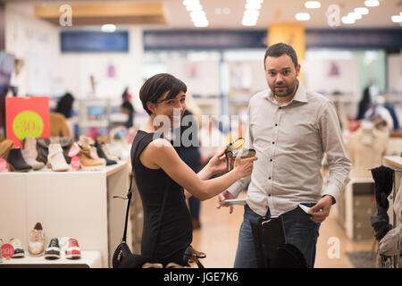 Un jeune beau couple change le regard avec de nouvelles chaussures Magasin de chaussures à Banque D'Images