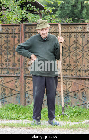 Un homme avec la fourche était sur la route pour un petit village dans la région de Maramures, Roumanie Banque D'Images