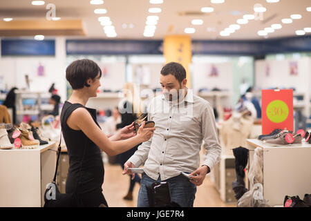 Un jeune beau couple change le regard avec de nouvelles chaussures Magasin de chaussures à Banque D'Images