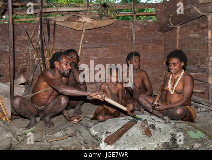 L'INDONÉSIE, JULIEN VILLAGE, GUINÉE - 24 juin : Famille tribu Korowai assise au coin du feu dans une maison traditionnelle. Tribu de Korowai (Kombai). Banque D'Images