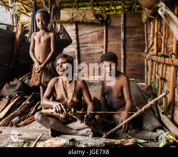 L'INDONÉSIE, JULIEN VILLAGE, GUINÉE - 24 juin : Famille tribu Korowai assise au coin du feu dans une maison traditionnelle. Tribu de Korowai (Kombai). Banque D'Images