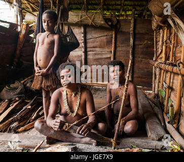 L'INDONÉSIE, JULIEN VILLAGE, GUINÉE - 24 juin : Famille tribu Korowai assise au coin du feu dans une maison traditionnelle. Tribu de Korowai (Kombai). Banque D'Images