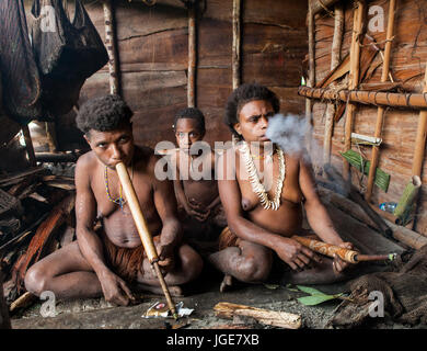 L'INDONÉSIE, JULIEN VILLAGE, GUINÉE - 24 juin : Famille tribu Korowai assise au coin du feu dans une maison traditionnelle. Tribu de Korowai (Kombai). Banque D'Images