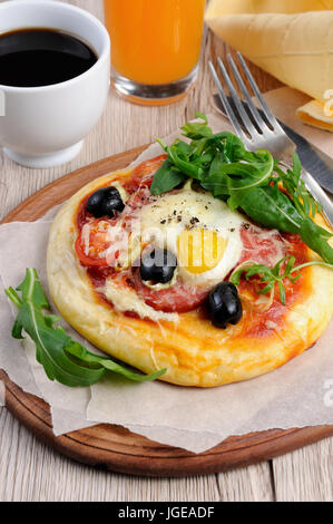 Mini pizza avec de la saucisse et l'oeuf et la roquette, une tasse de café pour le petit déjeuner Banque D'Images