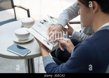 Deux jeunes hommes d'affaires dans les tenues de beau sourire, discuter dans un café. Banque D'Images