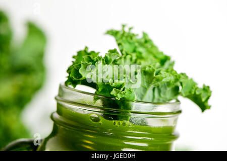 Un Smoothie kale servi dans un pot Mason surmontée d'une feuille de chou vert, sur un fond blanc Banque D'Images