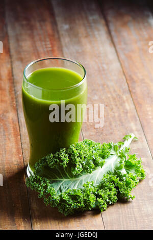 Un Smoothie kale servi dans un verre et une feuille de chou frisé, sur une table en bois rustique Banque D'Images