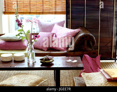 Table basse en bois simple et chaises en cuir brun longue avec coussins rose Banque D'Images