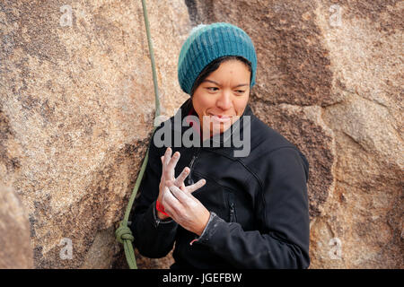 Young mixed race woman habillés en vêtements pour temps froid rock monte dans le désert Banque D'Images