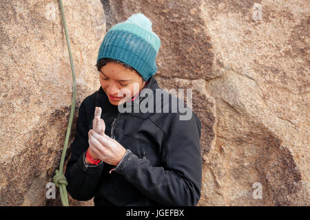 Young mixed race woman habillés en vêtements pour temps froid rock monte dans le désert Banque D'Images