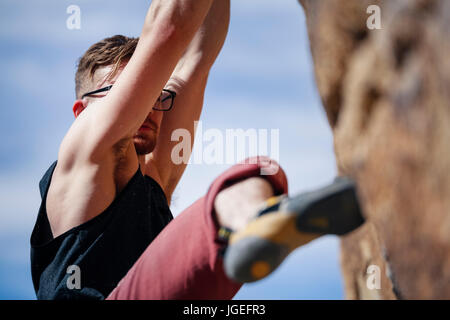 Les jeunes monter caucasian man with glasses rock monte dans le désert Banque D'Images