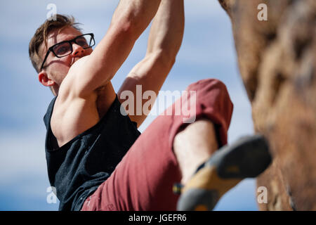 Les jeunes monter caucasian man with glasses rock monte dans le désert Banque D'Images