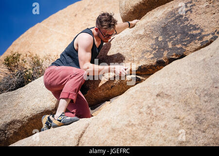 Les jeunes monter caucasian man with glasses rock monte dans le désert Banque D'Images