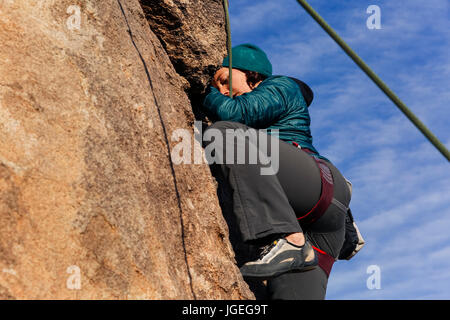 Young caucasian woman dressed for cold weather escalade dans le désert Banque D'Images