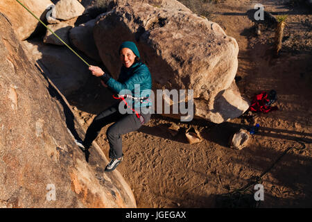 Young caucasian woman dressed for cold weather escalade dans le désert Banque D'Images