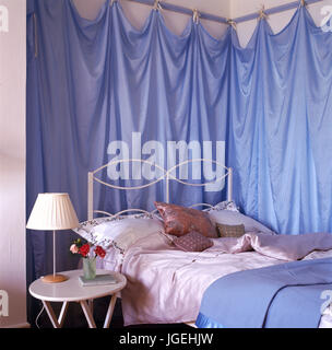 Coin de chambre avec des rideaux en tissu bleu sur les murs au-dessus de lit Banque D'Images