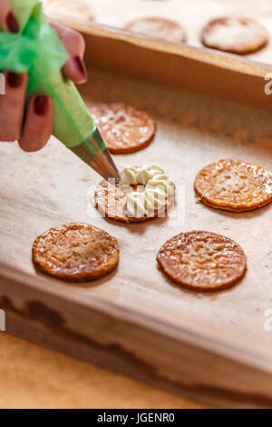 Main femme mille-feuille de décoration de gâteau avec la crème pâtissière Banque D'Images