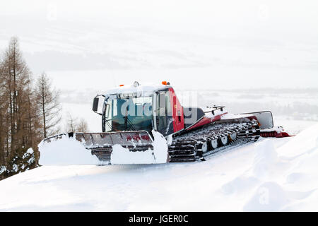 L'hiver rouge ratrak garé en pente dans la neige. Banque D'Images