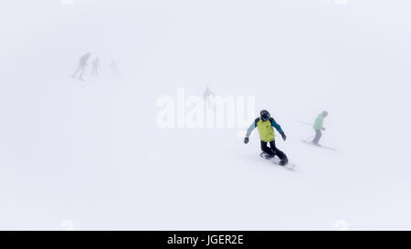 Skieurs et planchistes dans un brouillard épais sur la pente de ski dans la station de ski. Banque D'Images