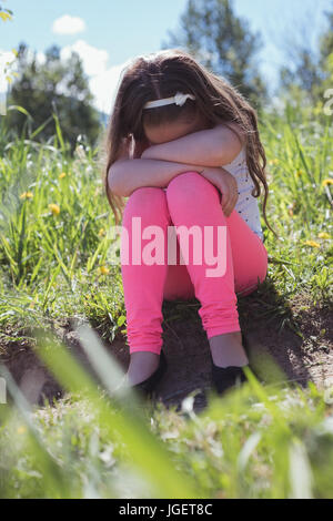 Triste fille assise dans un parc par une journée ensoleillée Banque D'Images