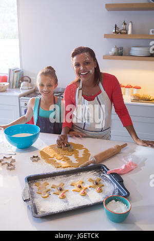 Portrait of smiling mother and daughter préparer les cookies dans plan de travail de cuisine à la maison Banque D'Images