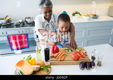 Aider grand-mère à petite-fille couper les légumes dans la cuisine à la maison Banque D'Images