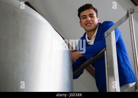 Low angle portrait of male worker par cuve de stockage à Brewery Banque D'Images